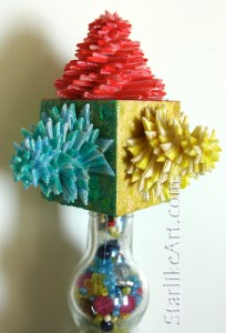 Leo Jean's Starlike© paper sculptures mounted on wooden cube atop glass