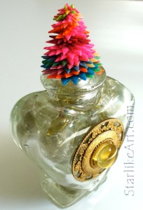 Leo Jean's Starlike© paper sculpture atop heart-shaped bottle full of glass stones